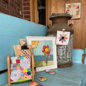 A collection of mini quilts displayed on a blue bench