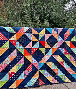 Scrappy star quilt on fence in nature