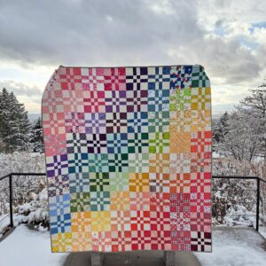 Scrappy disappearing four patch rainbow quilt in winter