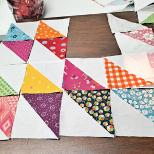 Half square triangles made in bright scrappy fabrics arranged into diamonds