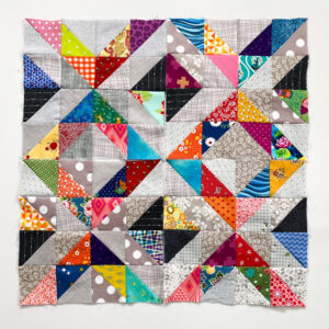 Half square triangles sewn in gray and scrappy brights arranged in squares and square in a square.