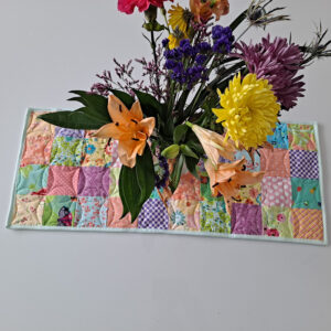 Flowers in a vase on a quilted spring table runner