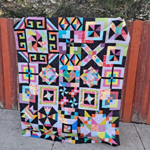 Colorful scrap quilt next to a fence