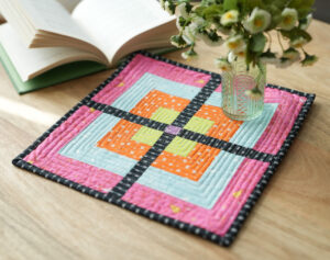 Modern quilted table topper with book and vase of flowers