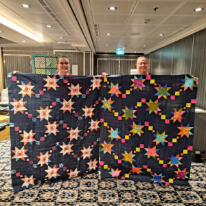 Two quilters holding their star quilts