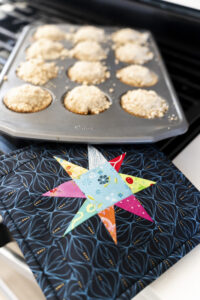Quilted wonky star hot pad with muffins in pan