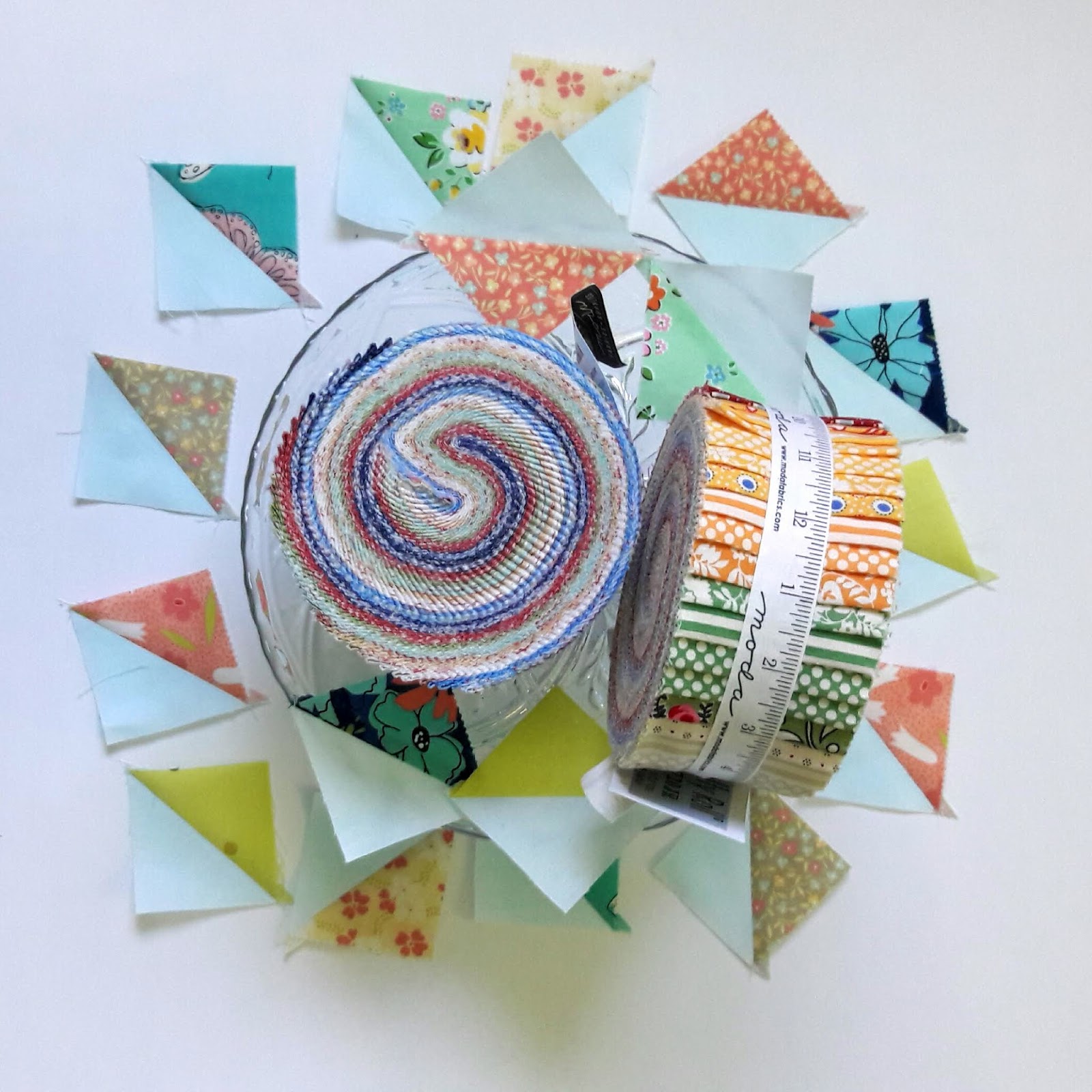 Fabric jellyrolls on a cake stand surrounded by half square triangles