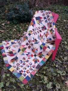 Scrappy Bear paw quilt draped on chair outside