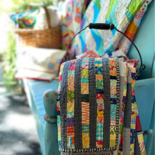 Scrap quilts draped on a blue bench