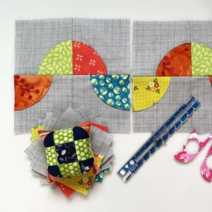 Drunkard's path blocks arranged in a row with pincushion, ruler and scissors