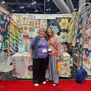 Erica from AccuQuilt Go visiting Aunt Em's booth at quilt market 