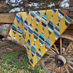 striped diamond baby quilt draped over wooden wagon