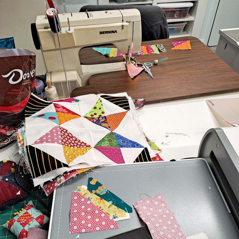 Bernina sewing machine with cut triangles ready to sew and a stack of quilt blocks.
