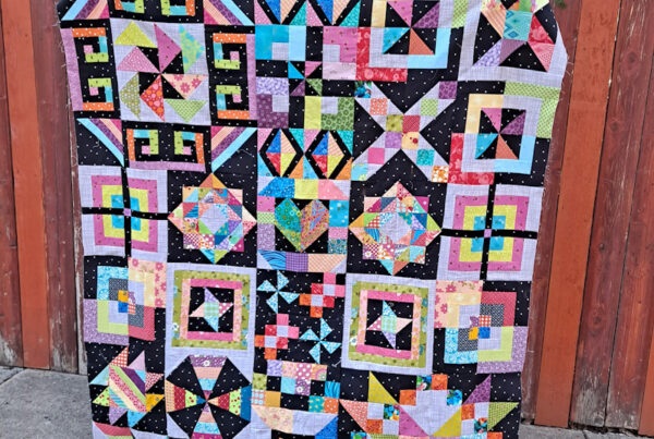 Colorful scrap quilt next to a fence