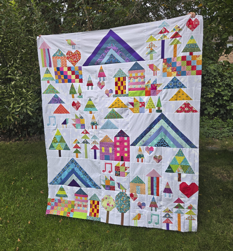 Colorful sampler quilt with trees, mountains and gnomes.