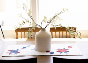 Vase with branches on a table with a red, white and blue table runner.
