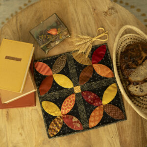 small table decorated with quilted fall table topper, books and a basket of bread.